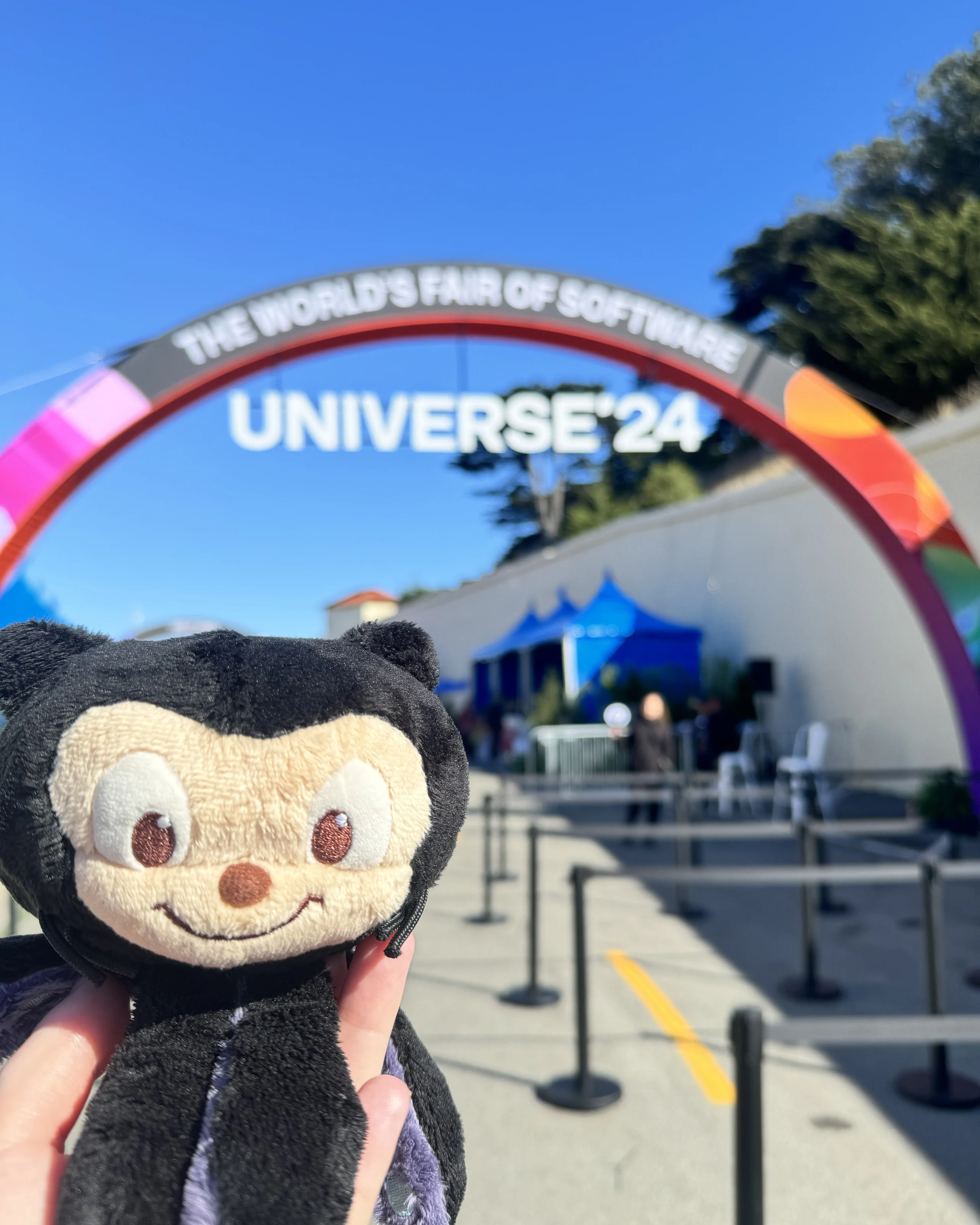 Mona the octocat plushie held up by a hand in front of the GitHub Universe 2024 entrance.